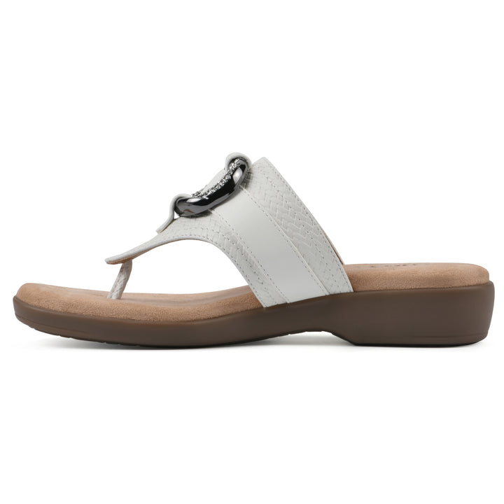 Side view of a light beige thong sandal with a centered metal ring ornament and tan sole