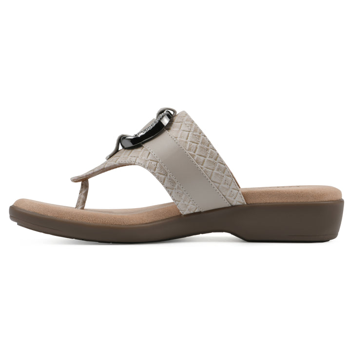 Side view of a light beige thong sandal with a centered metal ring ornament and tan sole