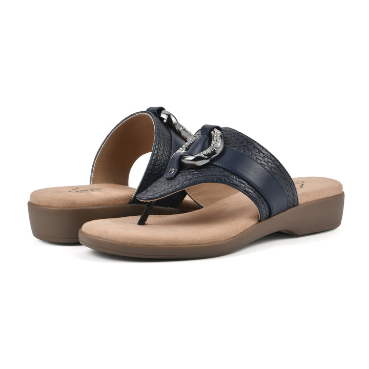 Angle view of a pair of navy thong sandals with a centered metal ring ornament and tan sole