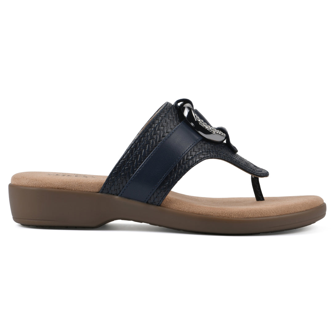 Side view of a navy thong sandal with a centered metal ring ornament and tan sole