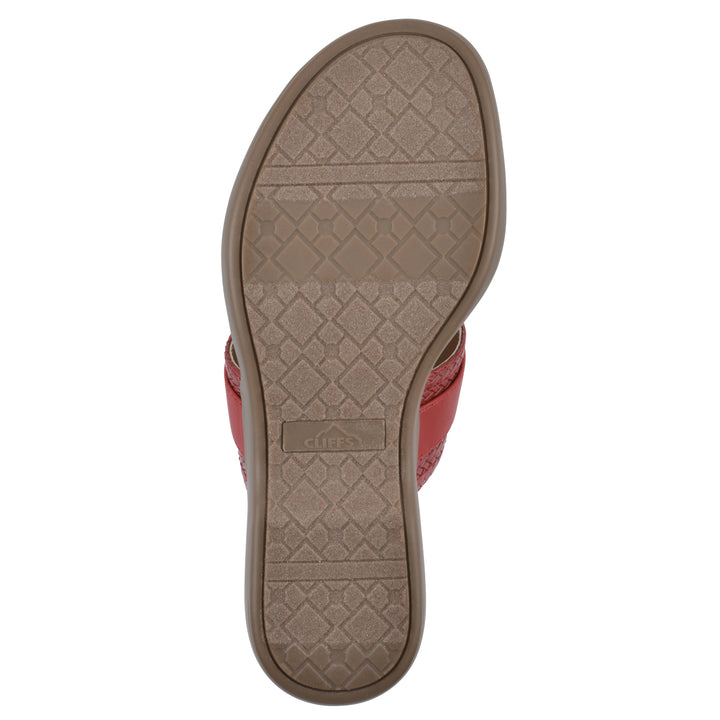 Sole view of a brick red thong sandal with a centered metal ring ornament and tan sole