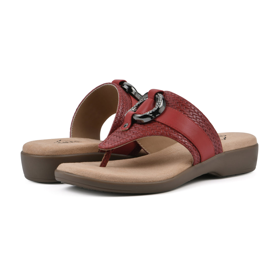 Angle view of a pair of brick red thong sandals with a centered metal ring ornament and tan sole