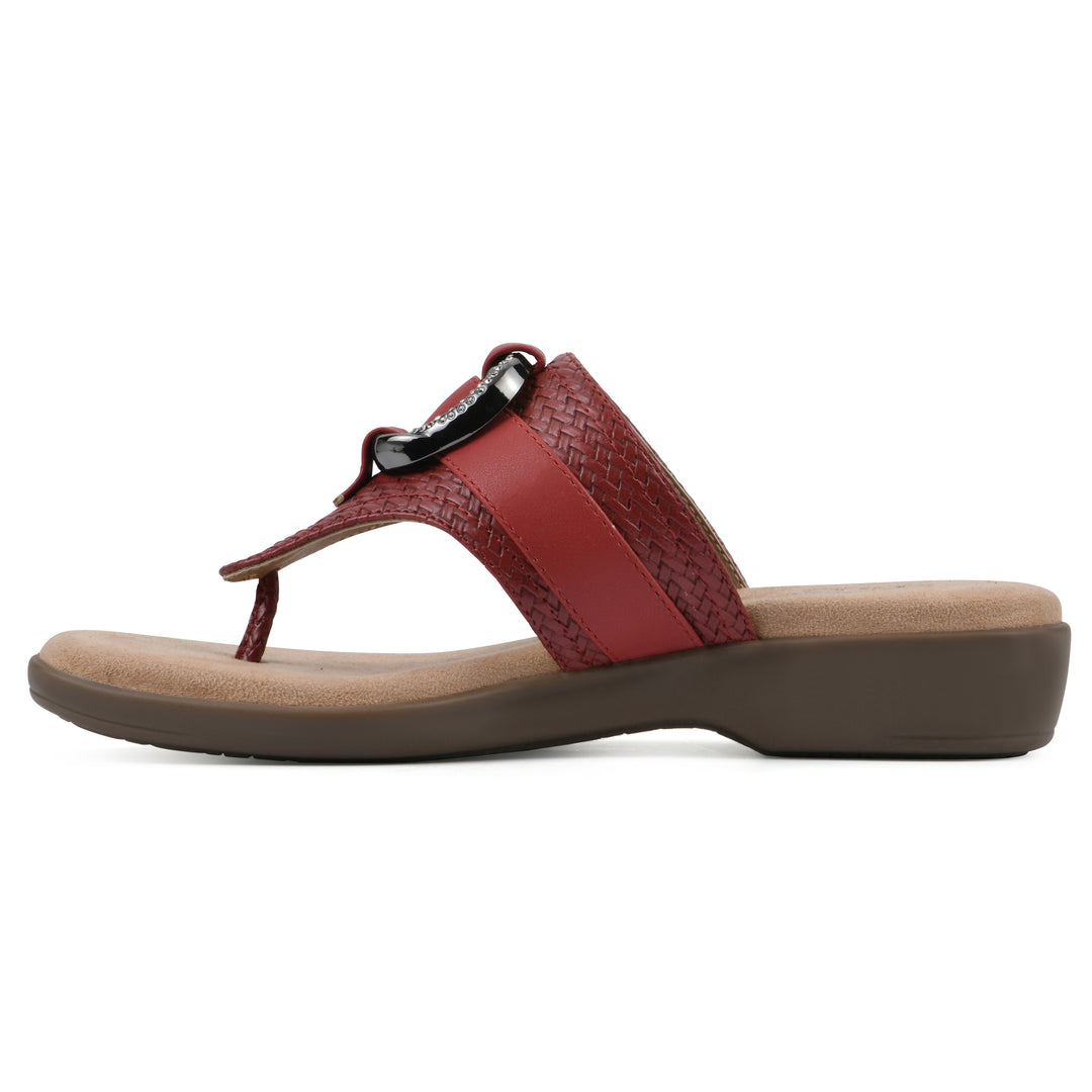 Side view of a brick red thong sandal with a centered metal ring ornament and tan sole