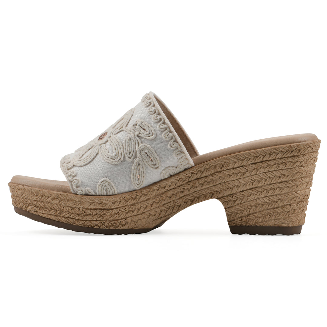 Side view of a white wedge sandal with cream embroidered floral pattern and a braided rope-style sole