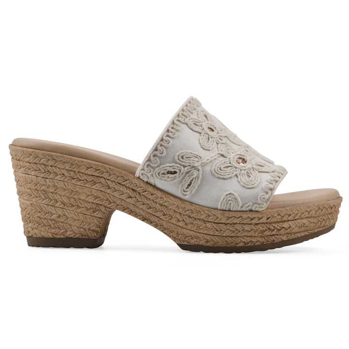 Side view of a white wedge sandal with cream embroidered floral pattern and a braided rope-style sole