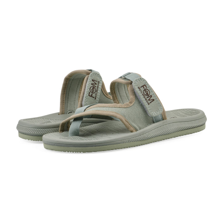 Angle view of a pair of sage fabric thong sandals with velcro center strap and a sage sole
