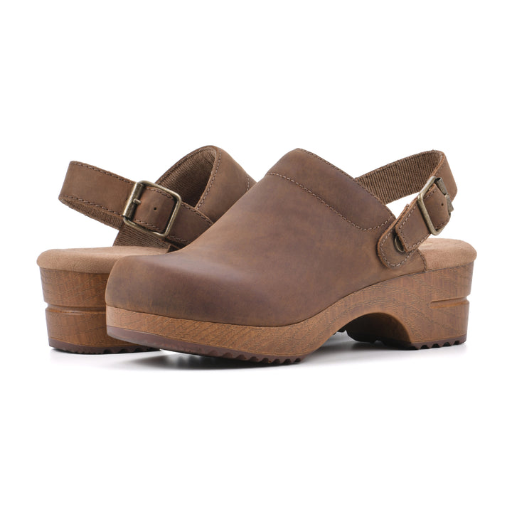 Angle view of a pair of backless brown leather clogs with adjustable back strap and wood style heel