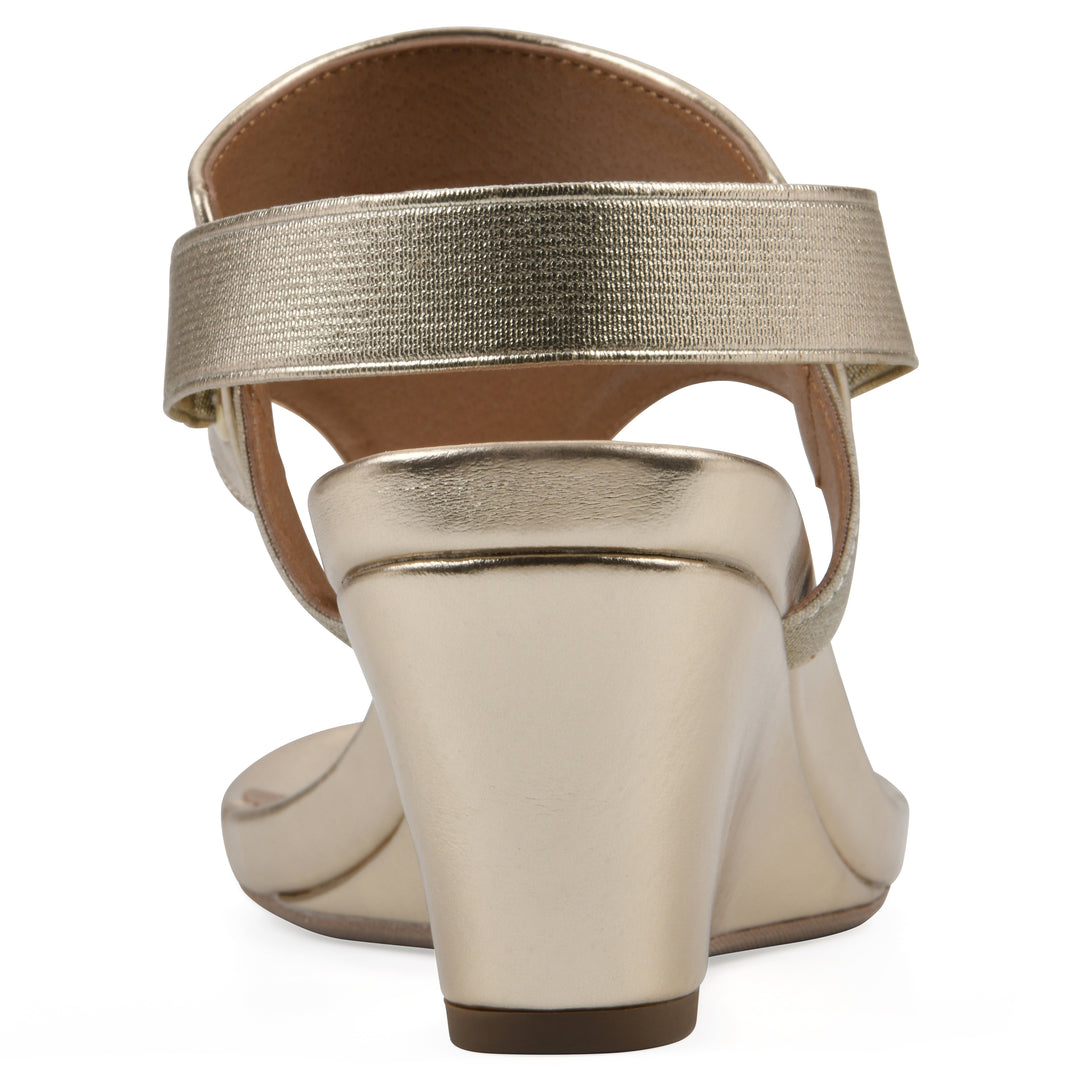 Rear view of a gold metallic thong wedge sandal with a wrapped heel, elastic ankle strap, and gold sole