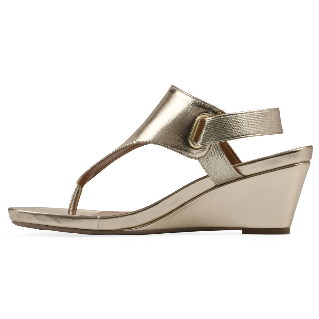 Side view of a gold metallic thong wedge sandal with a wrapped heel, elastic ankle strap, and gold sole