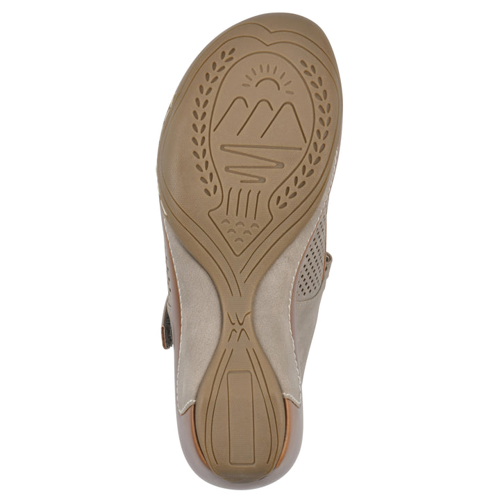 Sole view of a light taupe-colored clog with a closed toe and adjustable strap, featuring a perforated diamond design and a low heel.