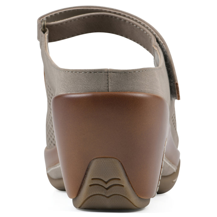 Rear view of a light taupe-colored clog with a closed toe and adjustable strap, featuring a perforated diamond design and a low heel.