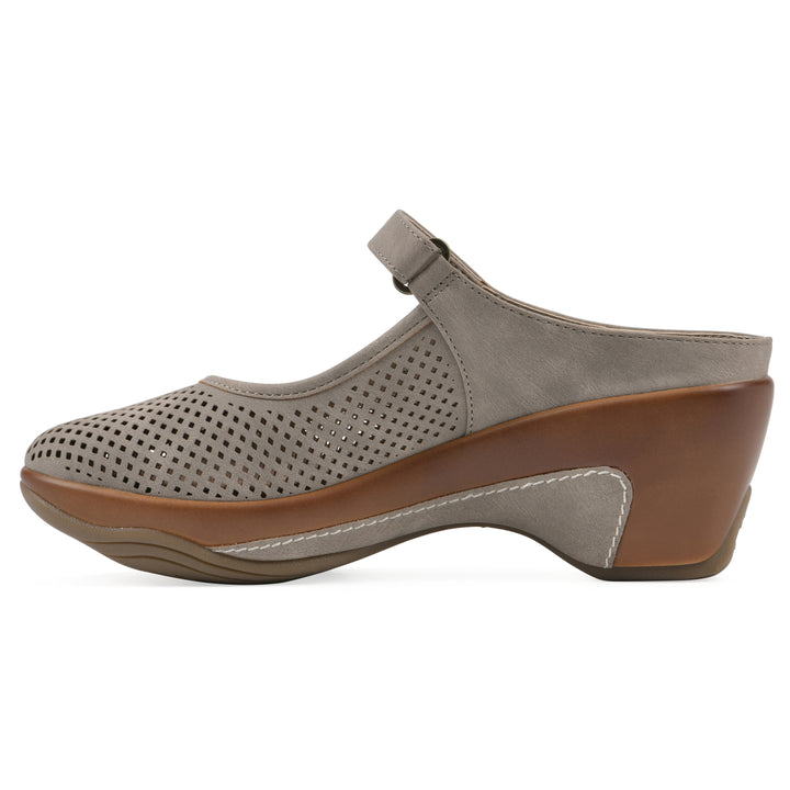 Side view of a light taupe-colored clog with a closed toe and adjustable strap, featuring a perforated diamond design and a low heel.