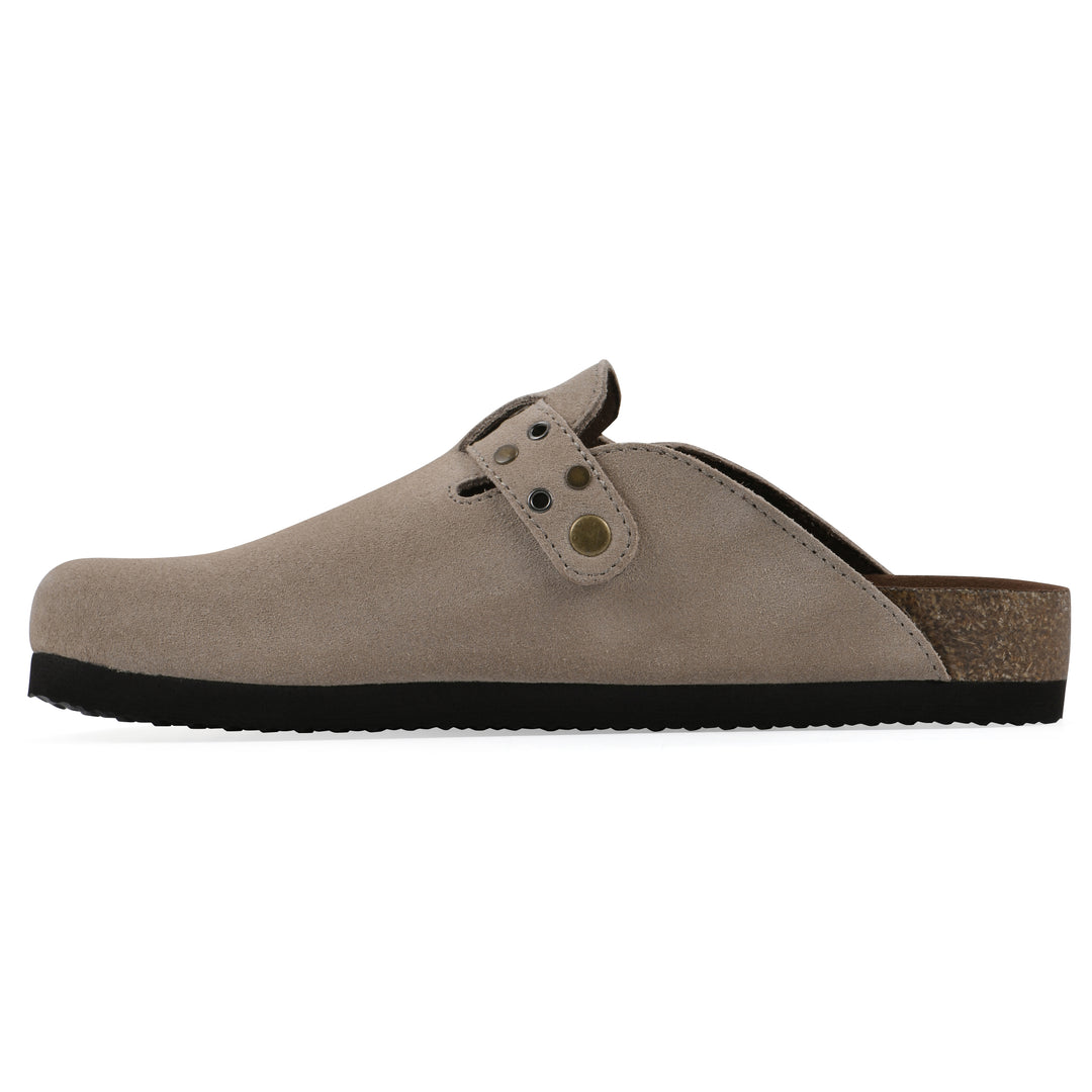 Side view of a tan suede backless clog with an adjustable buckle strap with stud and eyelet detailing and a black sole