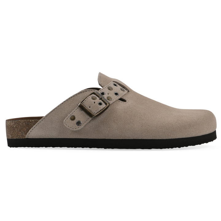 Side view of a tan suede backless clog with an adjustable buckle strap with stud and eyelet detailing and a black sole