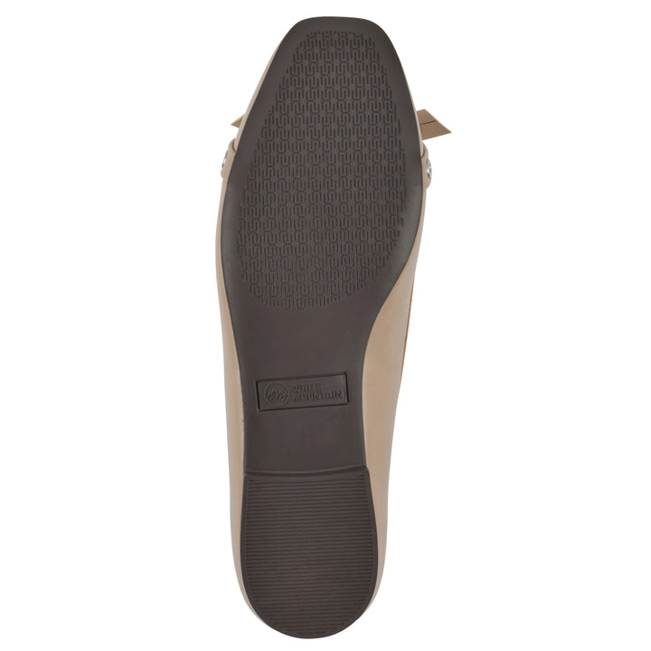 Sole view of a tan faux leather flat with small, centered bow, silver metal grommet lining and a black sole