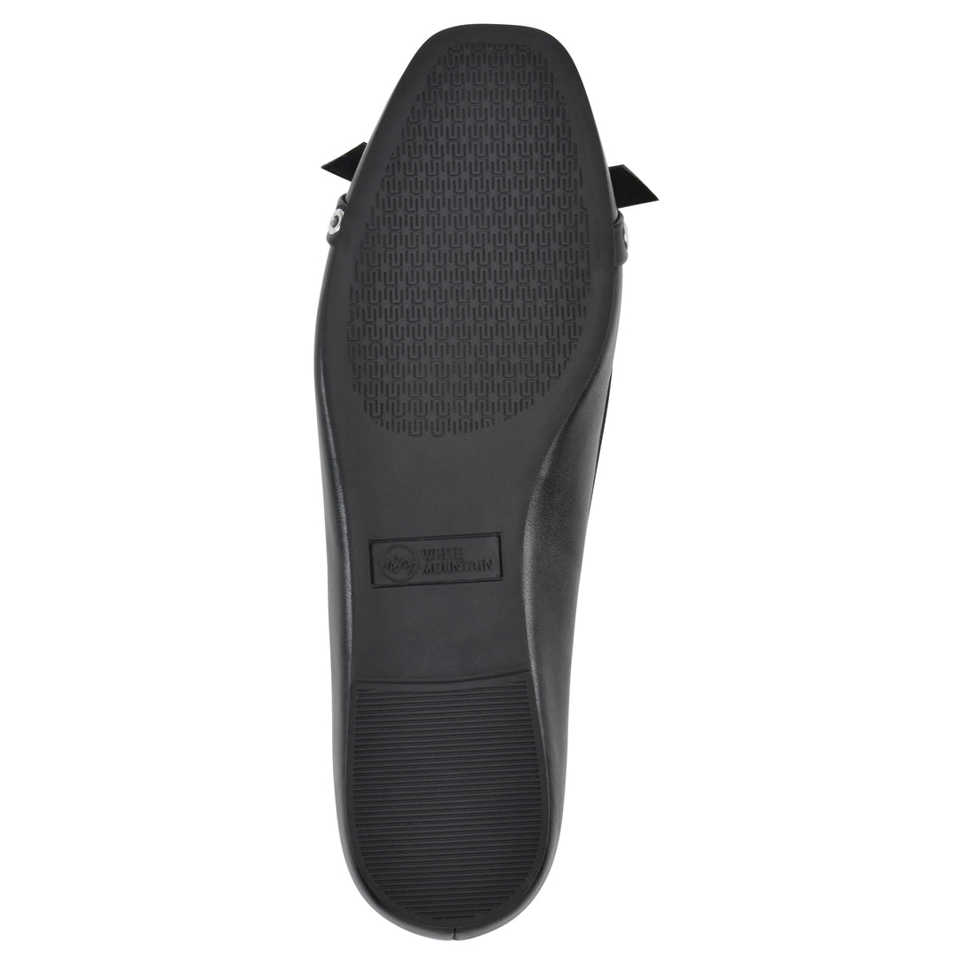Sole view of a black faux leather flat with small, centered bow, silver metal grommet lining and a black sole