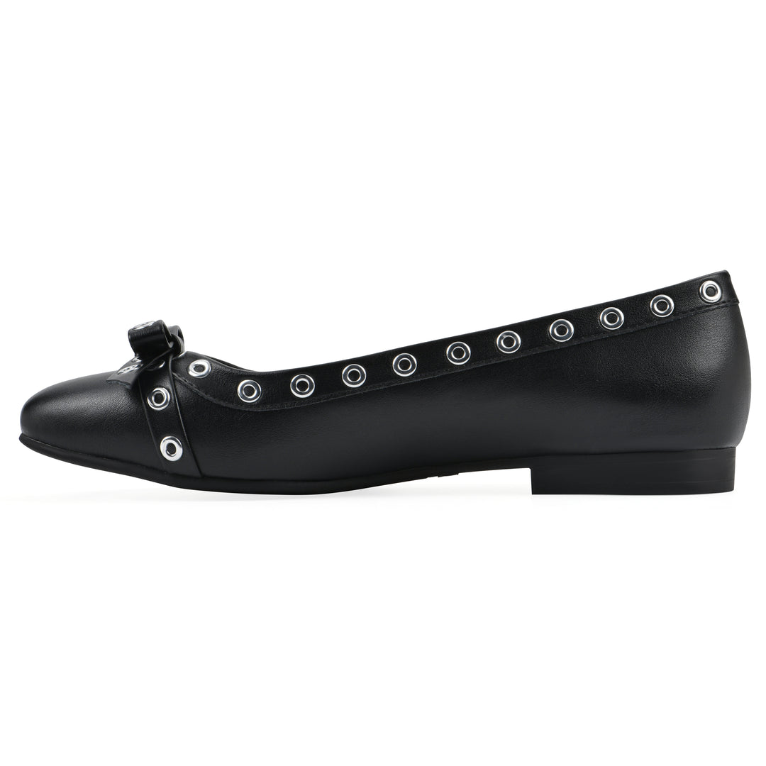 Side view of a black faux leather flat with small, centered bow, silver metal grommet lining and a black sole