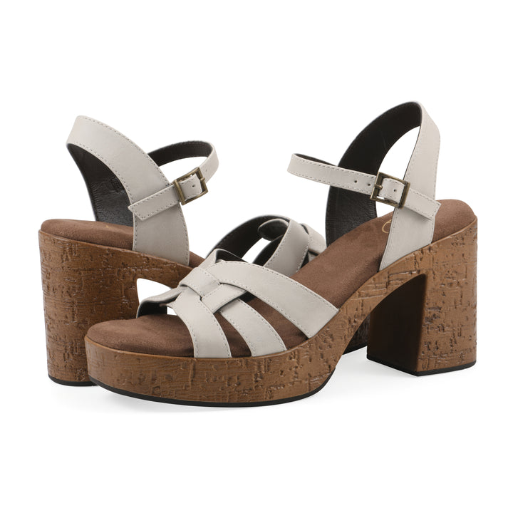 Angle view of a pair of cream faux leather platform sandals with buckle style ankle strap and a brown molded cork sole