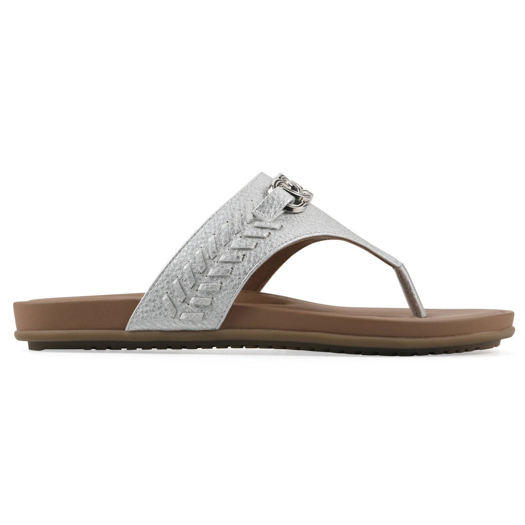 Side view of a silver thong sandal with metal embellishment and a brown sole