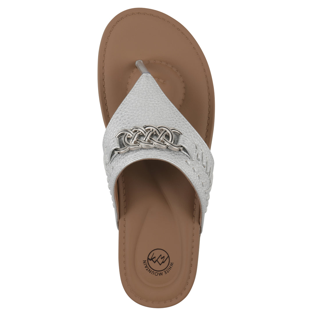 Top view of a silver thong sandal with metal embellishment and a brown sole