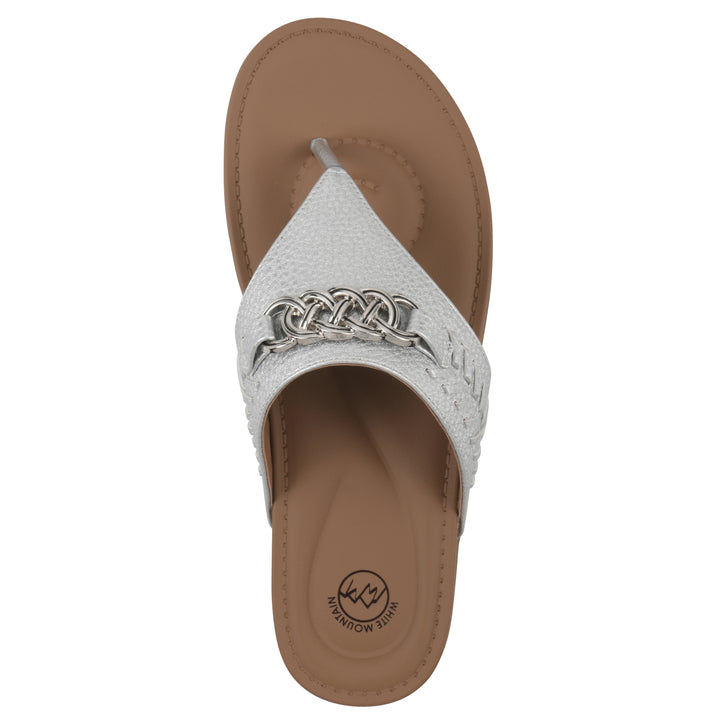 Top view of a silver thong sandal with metal embellishment and a brown sole