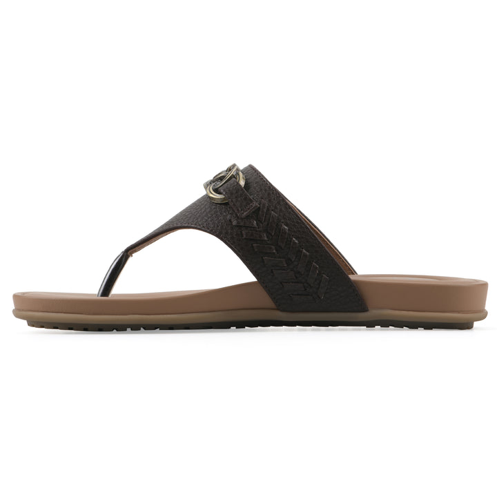 Side view of a brown thong sandal with metal embellishment and a brown sole