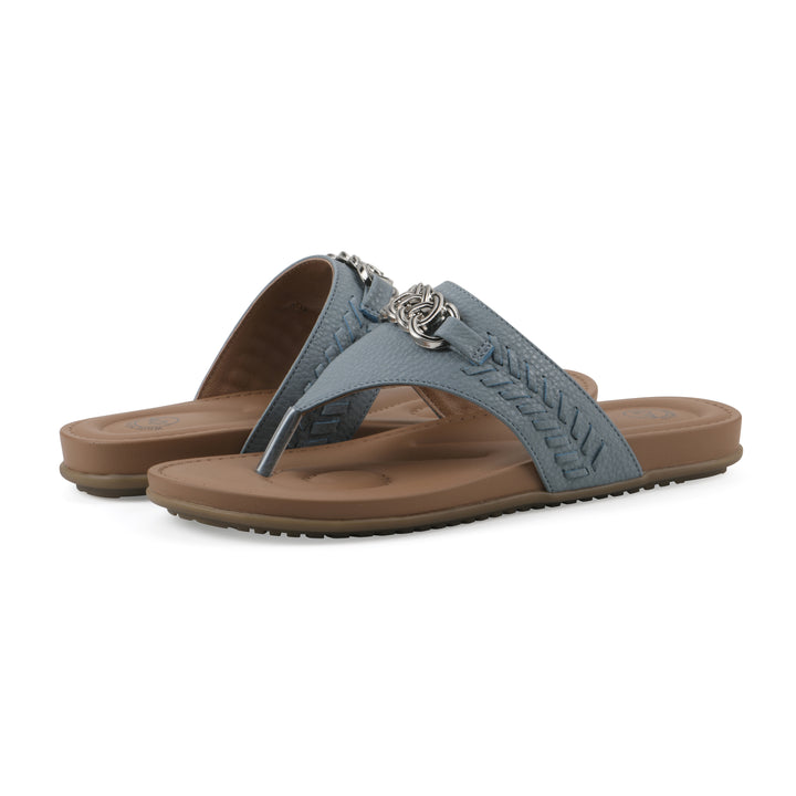 Angle view of a pair of blue thong sandal with metal embellishment and a brown sole