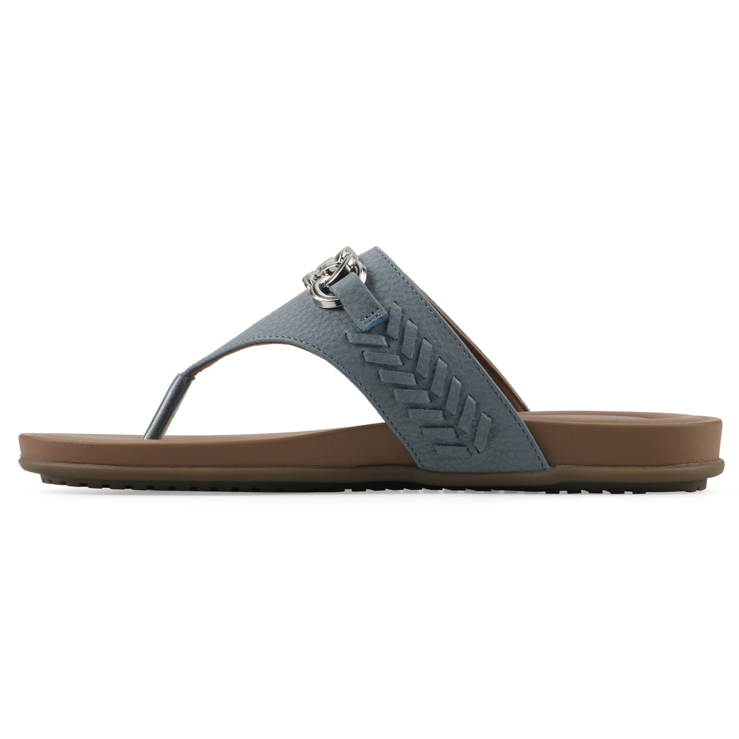 Side view of a blue thong sandal with metal embellishment and a brown sole