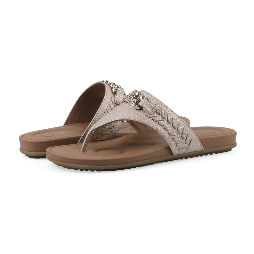 Angle view of a pair of light gold thong sandals with metal embellishment and a brown sole