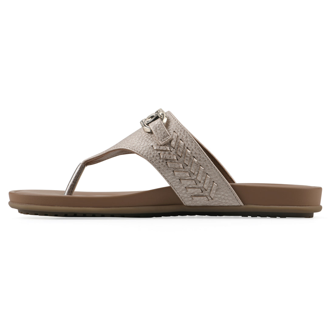 Side view of a light gold thong sandal with metal embellishment and a brown sole