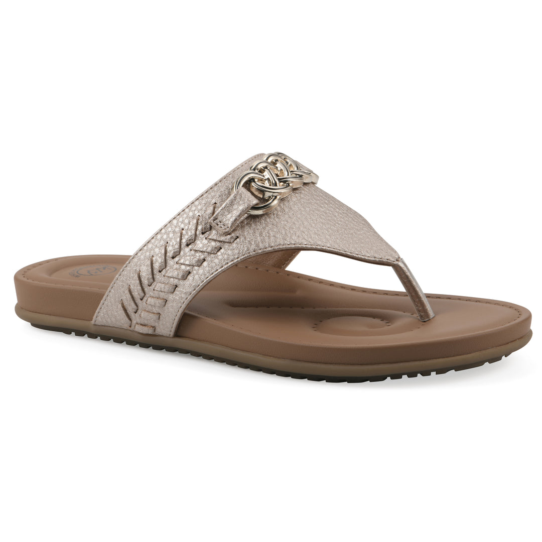 Angle view of a light gold thong sandal with metal emblem and a brown sole