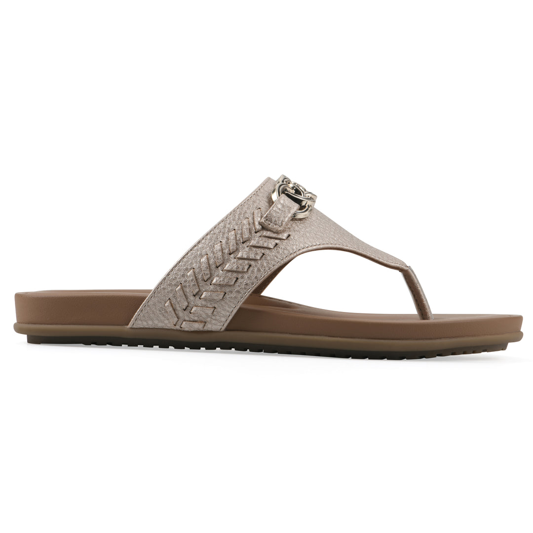 Side view of a light gold thong sandal with metal embellishment and a brown sole