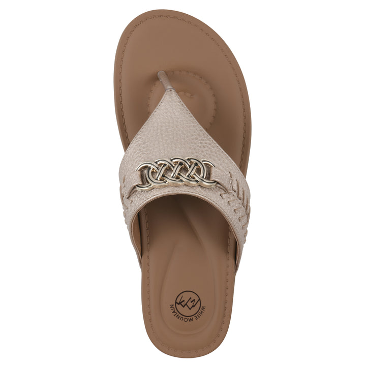 Top view of a light gold thong sandal with metal embellishment and a brown sole