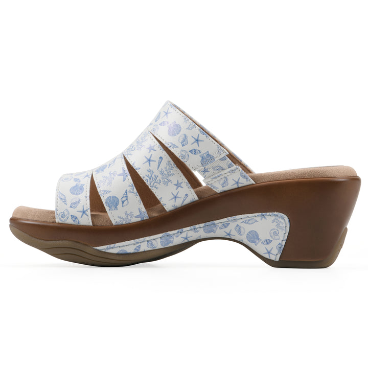 Side view of an open-toe mule sandal in white with a blue seashell pattern, a cushioned insole, and a brown heel 