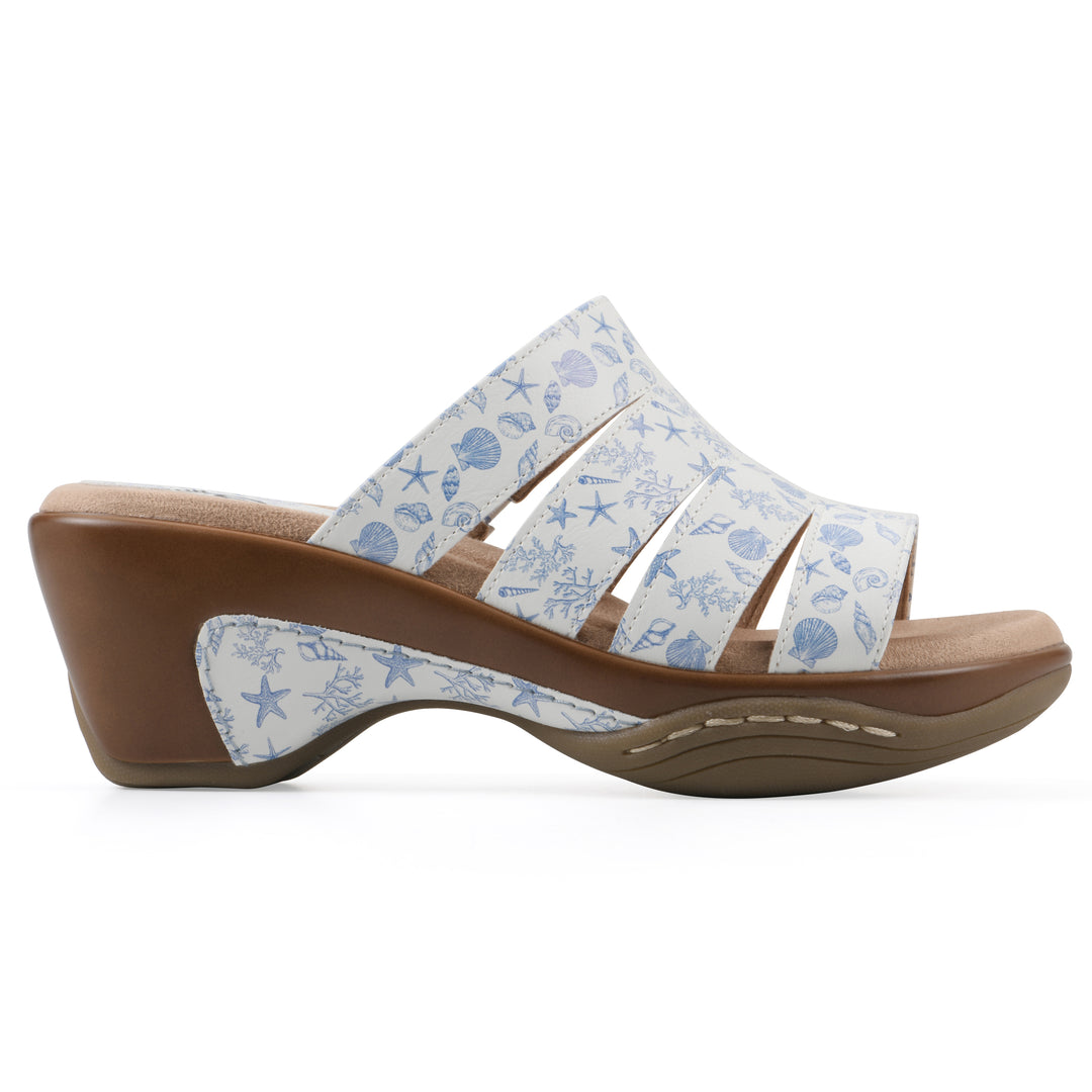 Side view of an open-toe mule sandal in white with a blue seashell pattern, a cushioned insole, and a brown heel 