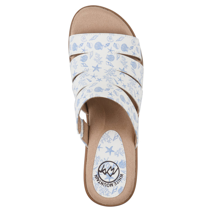 Top view of an open-toe mule sandal in white with a blue seashell pattern, a cushioned insole, and a brown heel 