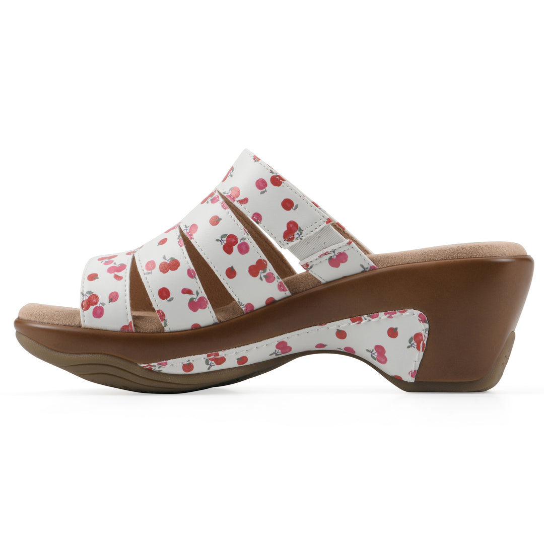 Side view of an open-toe mule sandal in white with a red cherry pattern, a cushioned insole, and a brown heel 
