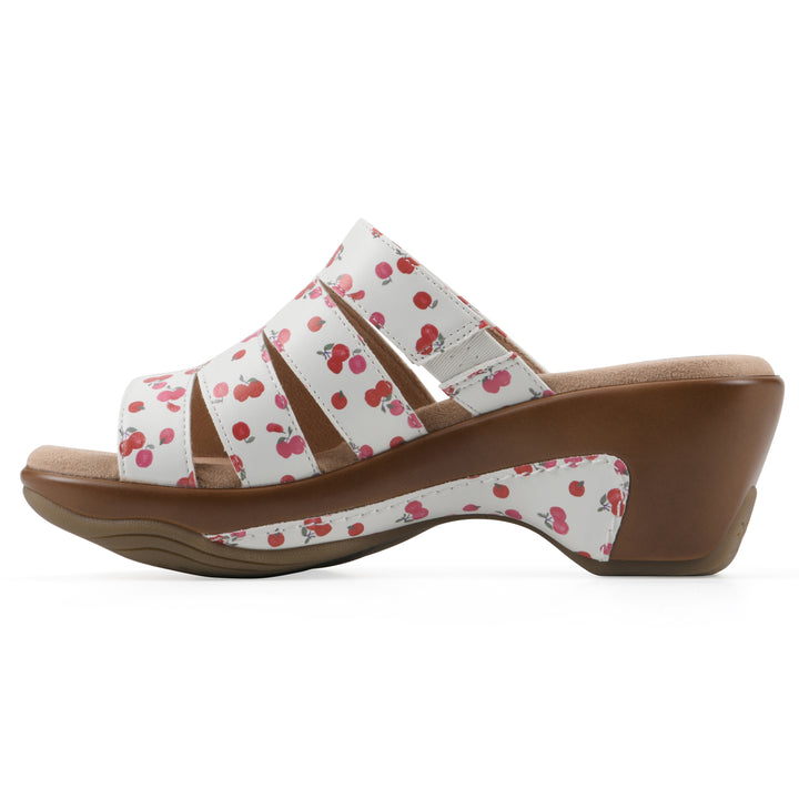 Side view of an open-toe mule sandal in white with a red cherry pattern, a cushioned insole, and a brown heel 