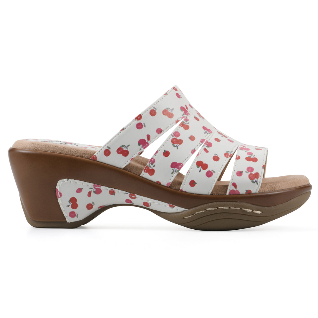 Side view of an open-toe mule sandal in white with a red cherry pattern, a cushioned insole, and a brown heel 
