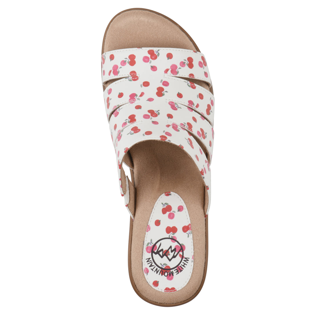 Top view of an open-toe mule sandal in white with a red cherry pattern, a cushioned insole, and a brown heel 